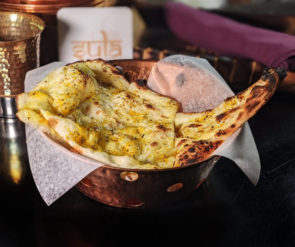 Freshly baked garlic naan with golden edges and chopped cilantro on top