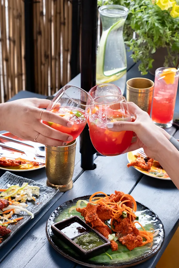 Cheers with cocktails over tandoori chicken at Sula happy hour, Vancouver