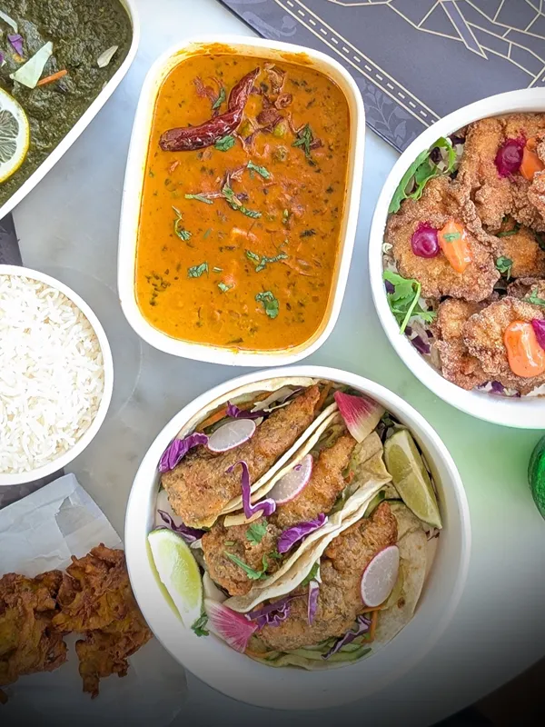 A carry out order of curry with basmati rice and freshly fried pakoras, packed in Sula containers.