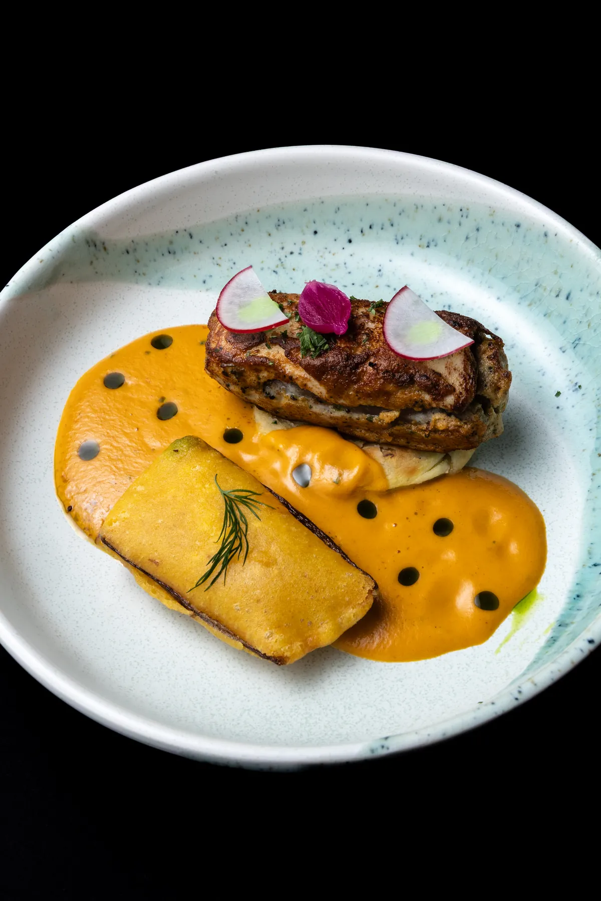 Nawabi Murg with fried raw banana, plated in a rich saffron-coloured gravy with radish and pickled petals.
